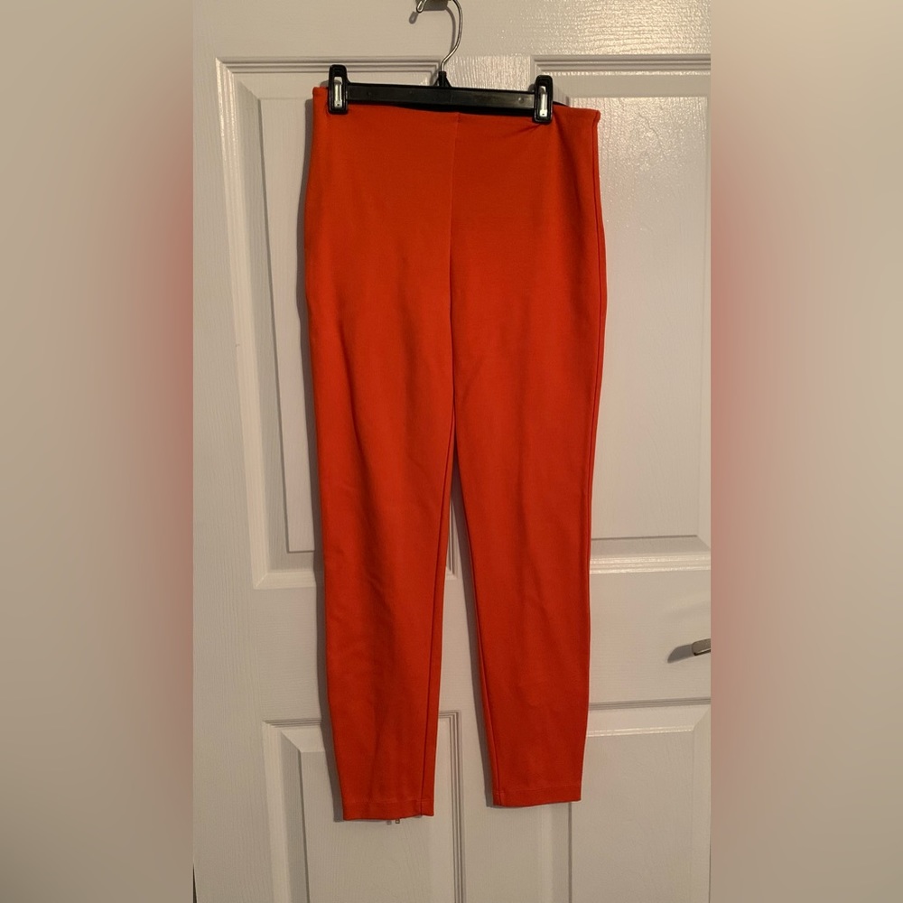 Orange stretchy pants with gold ankle zippers by Lysse
